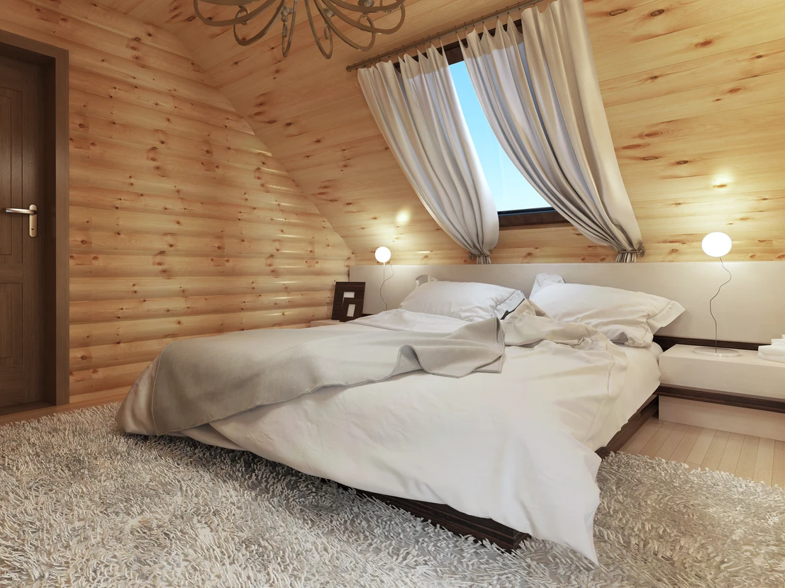 Chambre à coucher moderne dans chalet en bois avec lit double défait, linge blanc froissé