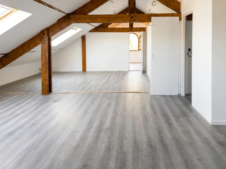 Intérieur résidentiel montrant l'angle d'une pièce avec murs peints en gris clair et plafond blanc